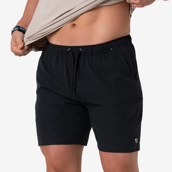 Man lifting his tee to show the Heather Black Athletic Short with drawstring waist, front view