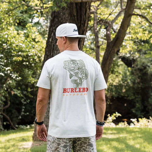 Man wearing a white t-shirt with a fish design and 'Burlebo Outdoors' branding, standing outdoors.