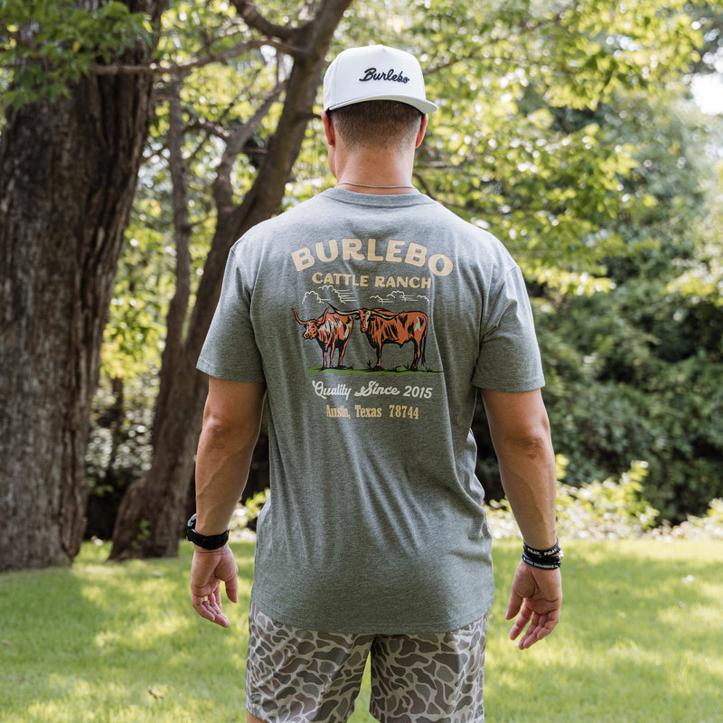 Man wearing a green t-shirt with 'Burlebo Cattle Ranch' design outdoors.