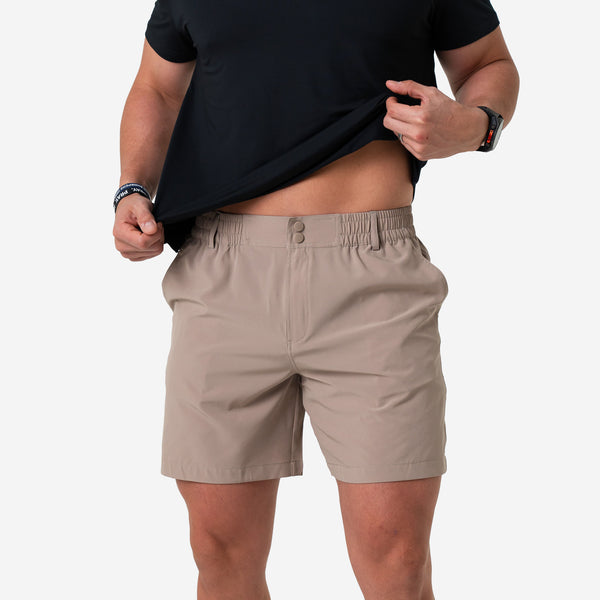 Front of the Cobblestone Khaki Everyday Short on a man lifting his black tee to show the two-snap waistband
