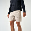 Person wearing beige shorts and a black long-sleeve shirt on a white background