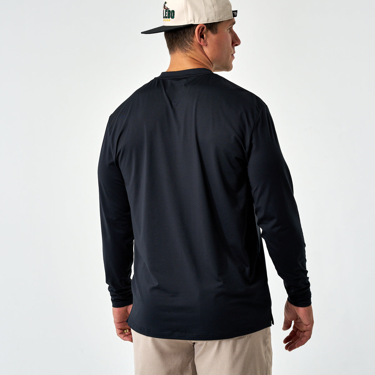 Back view of a man wearing the Black Long Sleeve Go To Tee and a cream cap