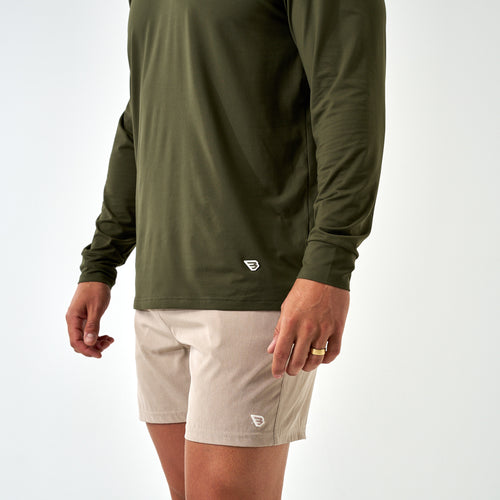 Close-up of the Mallard Green Long Sleeve Go To Tee hem with a small white B logo, worn with khaki shorts