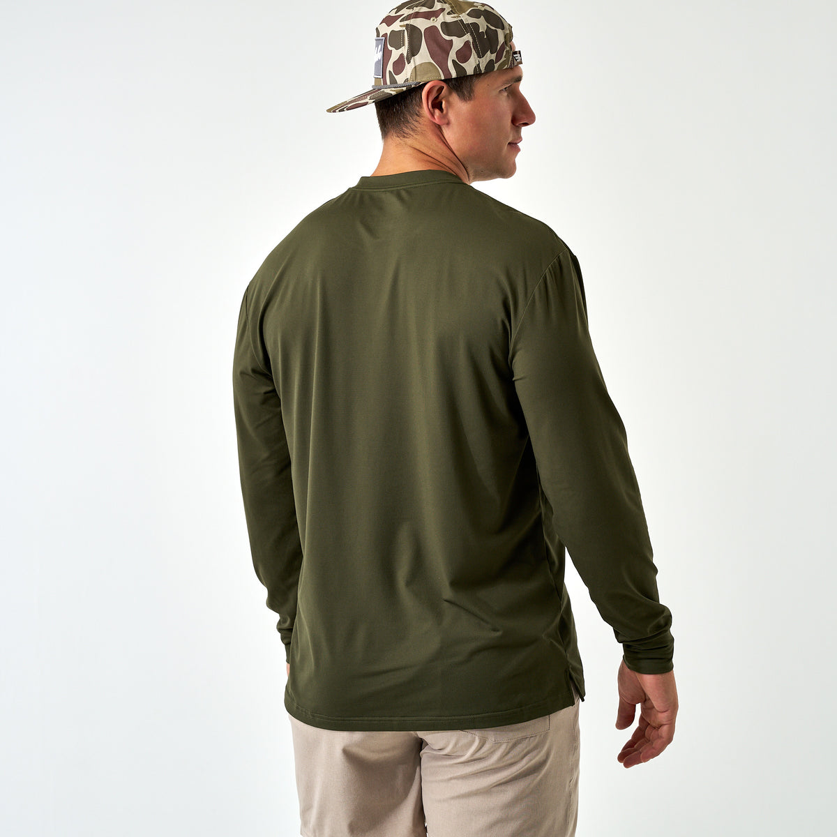 Back view of a man wearing the Mallard Green Long Sleeve Go To Tee and a camo cap