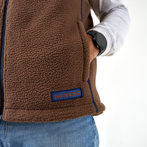Close-up of the Multi Brown Montana Vest hand pocket and navy BURLEBO patch on brown sherpa