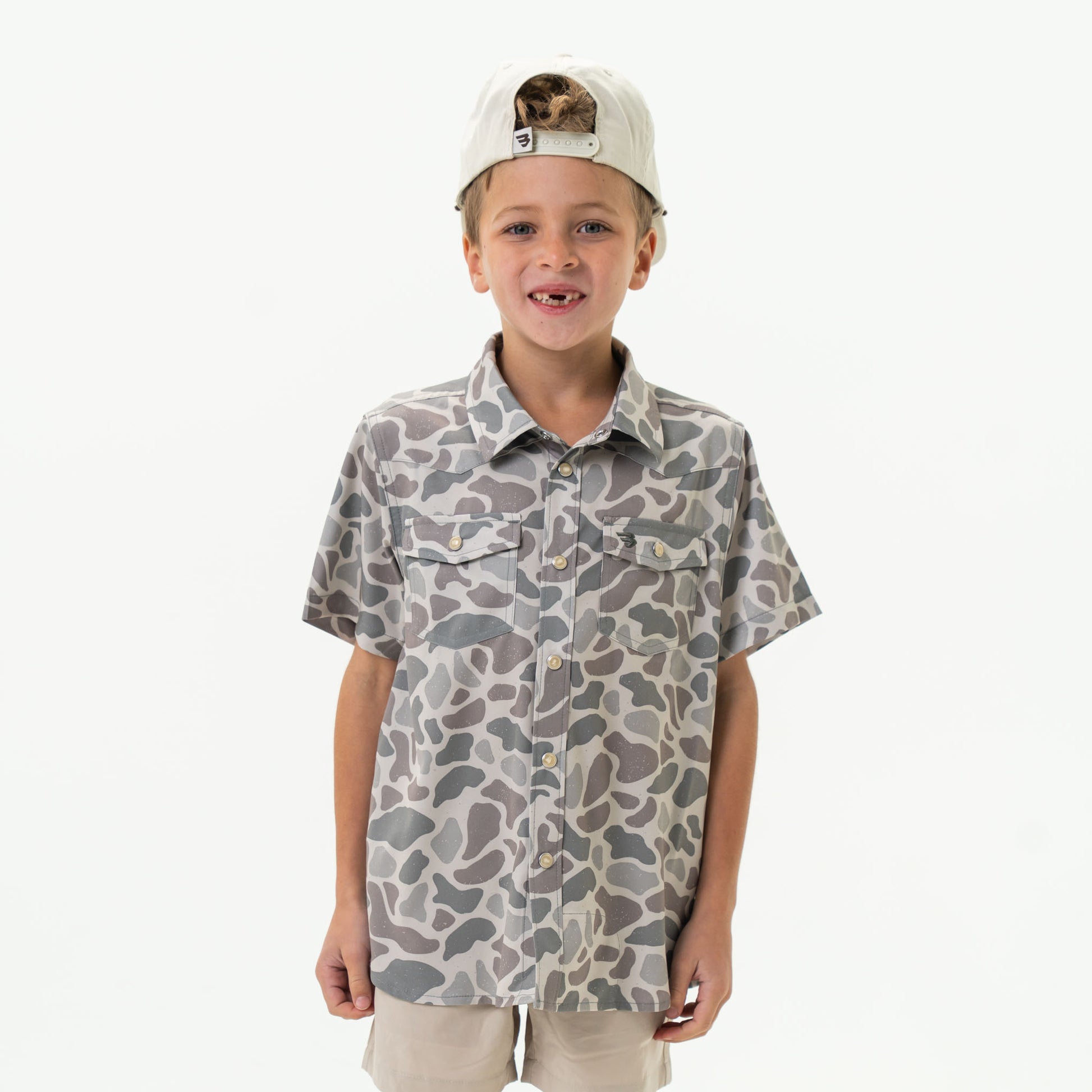 Child wearing a camouflage-patterned shirt and cap on a white background
