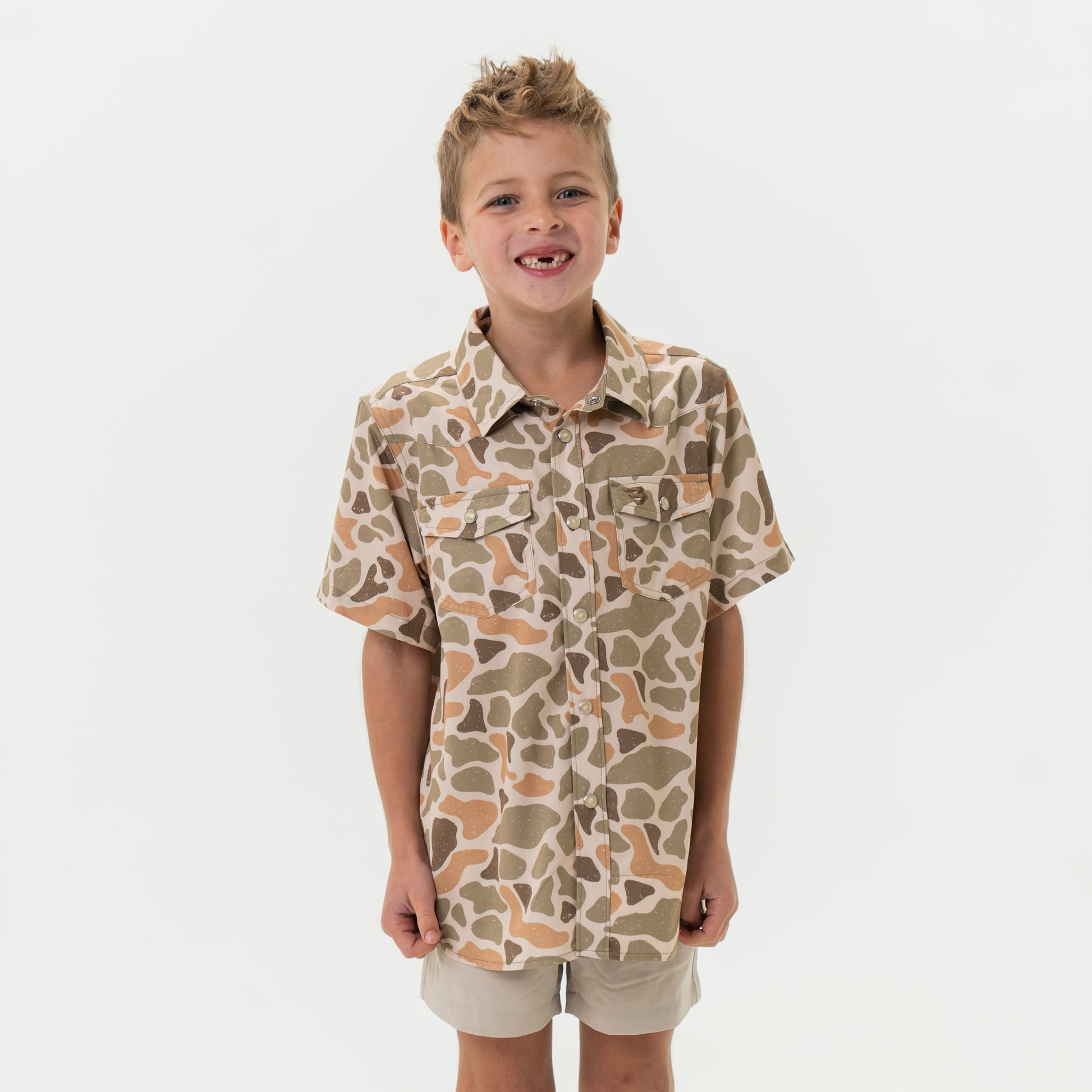 Child wearing a camouflage shirt and shorts on a white background
