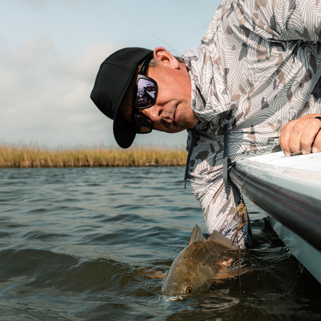Man in a boat holding a fish on a lake