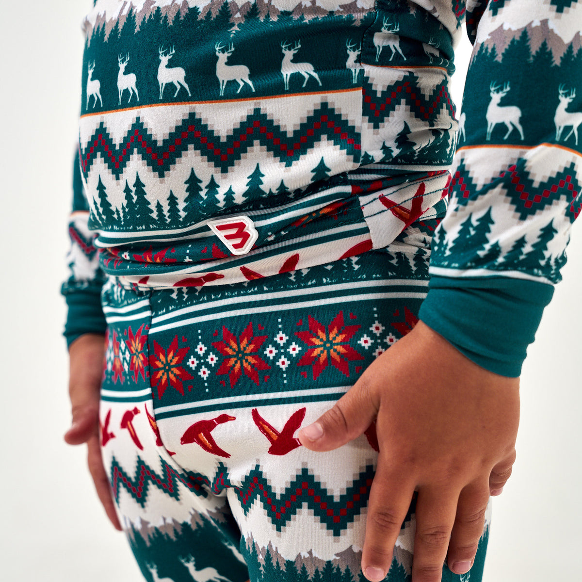 Close-up of the waistband logo tag and Fair Isle deer, poinsettia, and red duck print on the Christmas Youth Pajama Set