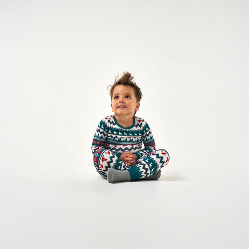 Toddler sitting on the floor in the BURLEBO Outdoors Christmas Youth Pajama Set, looking up